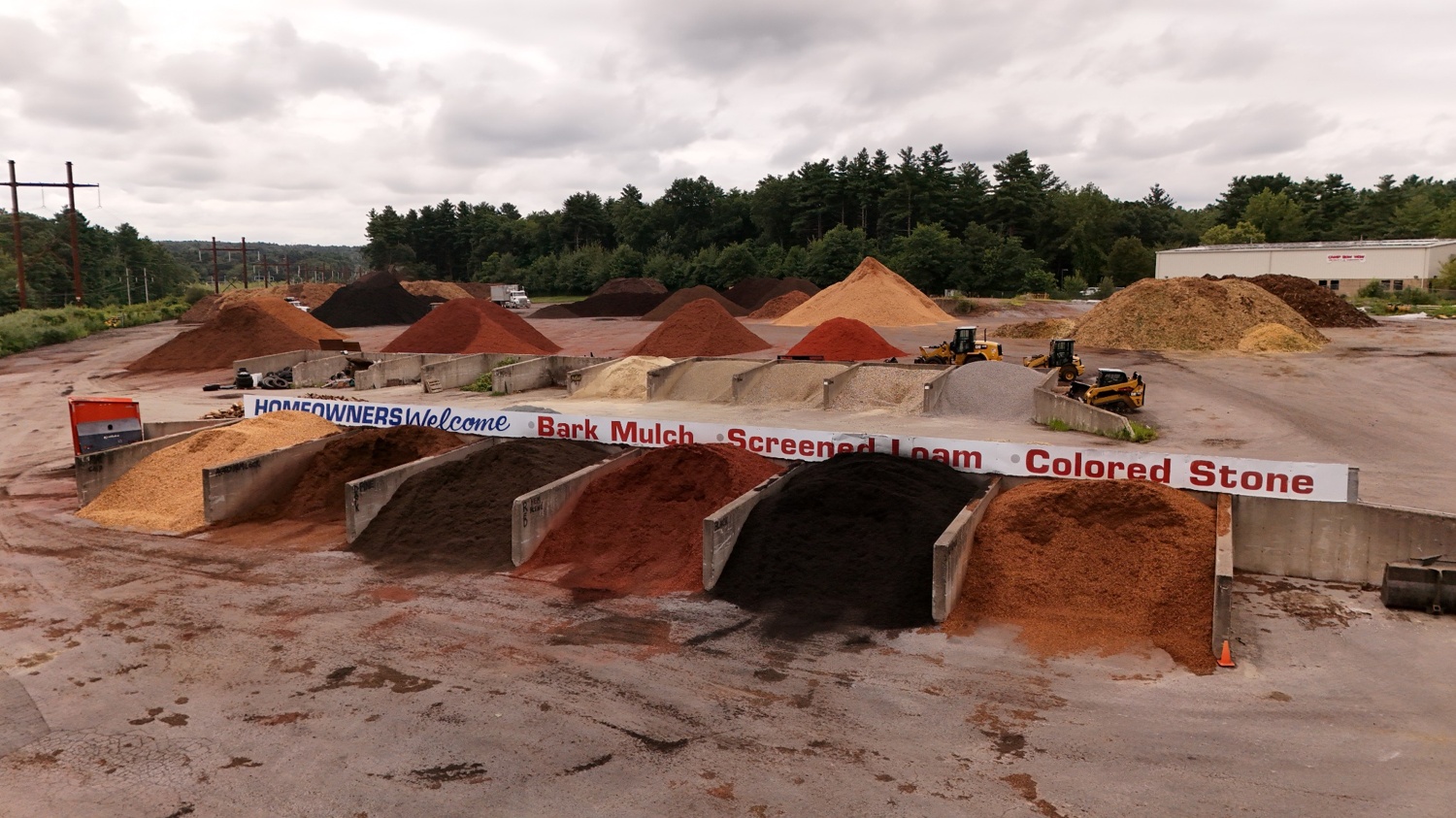 Bulk mulch piles in a landscape supply yard in Bellingham MA showing different mulch types available for delivery